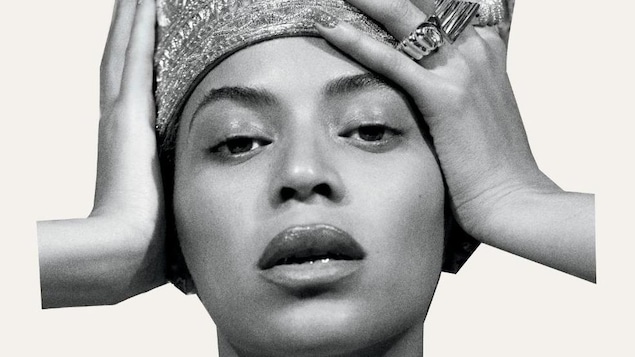 Visage de Beyoncé en noir et blanc. Elle porte une tiare et des grosses bagues. Elle se tient la tête à deux mains.