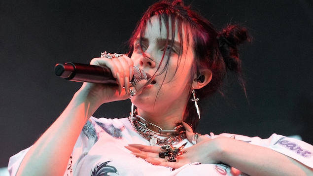 Billie Eilish sur scène avec de longs ongles et beaucoup de bijoux.