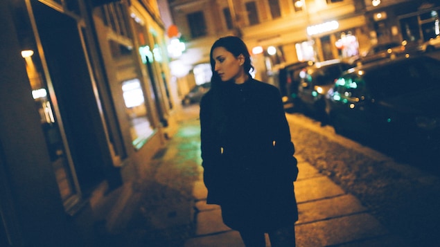 Une jeune femme marche avec inquiétude dans la rue le soir.