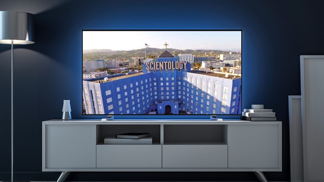 Une télévision montrant l'Église de Scientologie de Los Angeles dans un salon bleu.