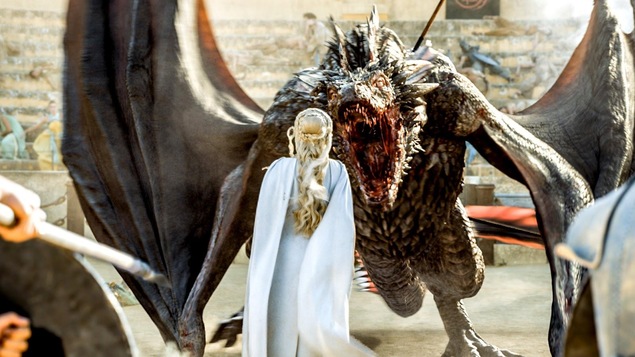 On voit Daenerys Targaryen (Emilia Clarke) de dos, avec un immense dragon, la bouche ouverte, qui s'approche d'elle. La scène est tirée de la série « Game of Thrones ».