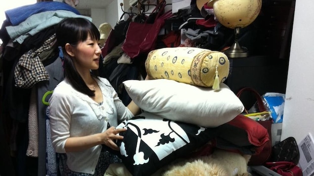 Marie Kondo, l'air ébahi, devant une immense pile d'objets.
