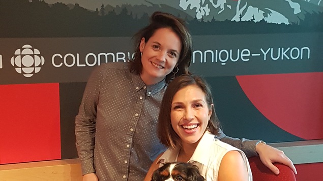 Deux femmes sont dans un studio de radio et l'une d'elles tient dans ses bras un petit chien.
