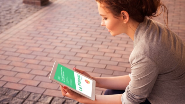 Une lectrice lit son journal hyperlocal sur une tablette.