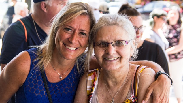 Deux femmes font une accolades en regardant vers le photographe.