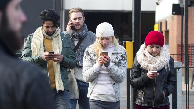 Trois d'entre eux regardent leur cellulaire tout en marchant, tandis qu'un autre parle au téléphone.