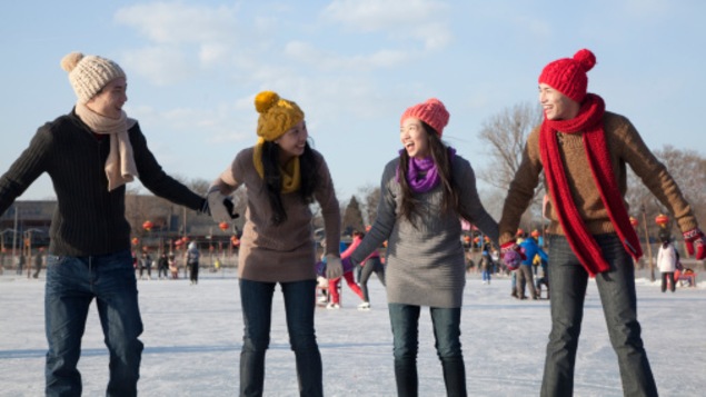 Quatre personnes se tiennent par la main sur une patinoire extérieure.