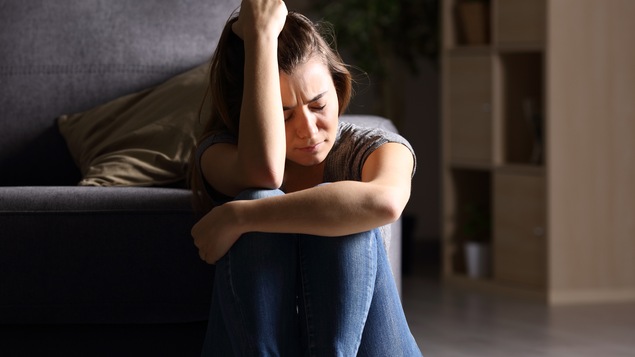 Une femme est assise par terre et semble avoir de la peine