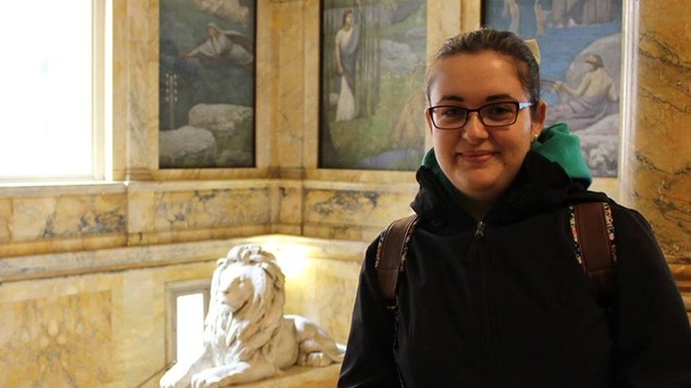 Pénélope Doucet dans la bibliothèque de Boston (près d'une statue de lion en plâtre et des fresques sur les murs)