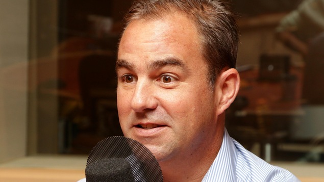 Geoff Molson devant un micro de radio.