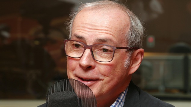 Photo de René Laprise devant un micro de radio.