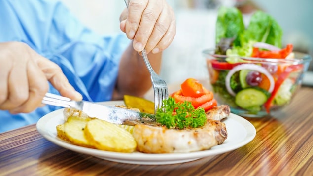 Un homme coupe un morceau de viande dans une assiette.