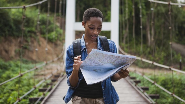 Photo d'une femme qui lit une carte sur un pont dans une forêt.