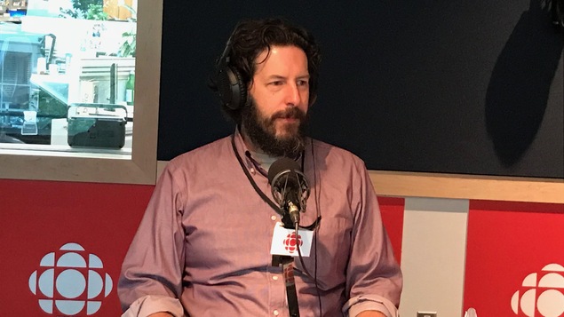 Un homme est assis devant un micro dans un studio de radio.