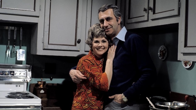 Photo prise sur le plateau de Quelle famille!, Janette Bertrand et Jean Lajeunesse sont enlacés dans la cuisine du plateau de télévision. Photo prise sur le plateau de Quelle famille!, Janette Bertrand et Jean Lajeunesse sont enlacés dans la cuisine du plateau de télévision.