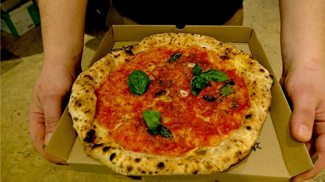 Une pizza recouverte de sauce tomate et de feuilles de basilic