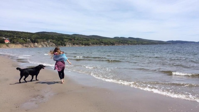 Une femme marche avec son chien sur la plage sablonneuse de Cap-aux-Os