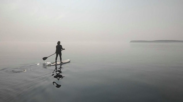 Une personne à planche à pagaie navigue dans la brume au large du Havre-Saint-Pierre.