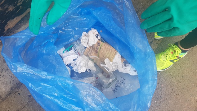 Un sac de déchets tenu par une personnes en chaussures de courses.