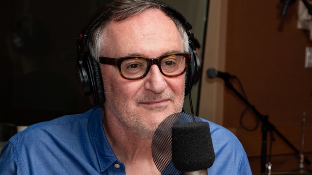 Affublé de lunettes sombres, le comédien regarde l'animatrice.