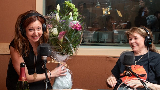 La journaliste sourit en brandissant le bouquet de fleurs de la gagnante.