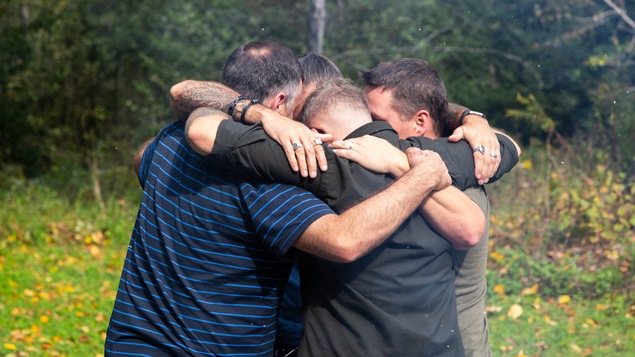 Sébastien Goulette, Dominique Brière, Frédérick Lavergne et Érick Moyneur se prennent dans leur bras, en forêt, à leur retour de Bosnie.