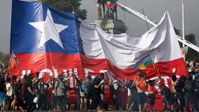 Des manifestations devant un immense drapeau chilien.