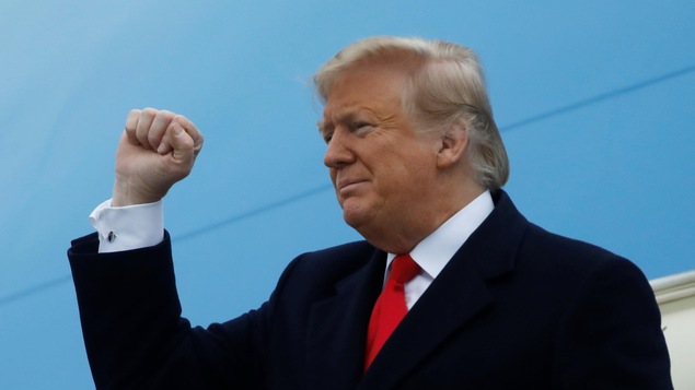 Donald Trump en veston cravate levant son poing droit.