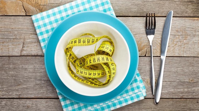 Un ruban mesurant le tour de taille placé dans une assiette.