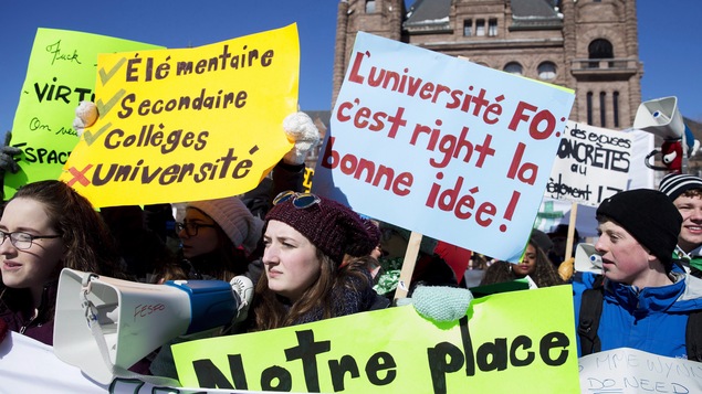 Des étudiants de l’École Veronique Mortimer manifestent devant Queen’s Park à Toronto. Ils tiennent des pancartes avec des slogans comme L'université FO c'est right la bonne idée