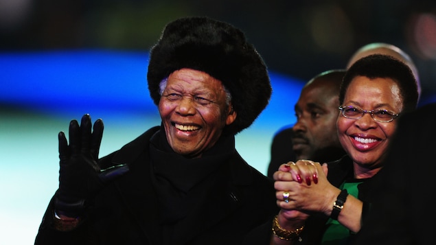 L'ancien président sud-africain Nelson Mandela salue la foule en compagnie de sa femme Graça Machel lors de la Coupe du Monde de 2010, en Afrique du Sud.