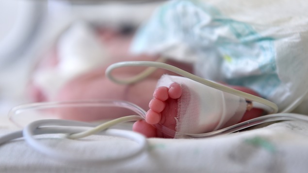 Le pied d'un bambin sur un lit d'hôpital