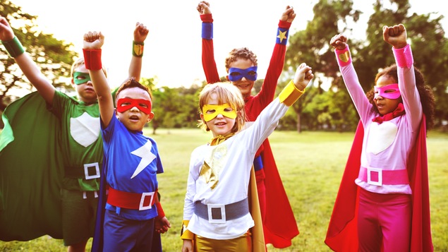 Des enfants déguisés en super-héros lèvent le poing.