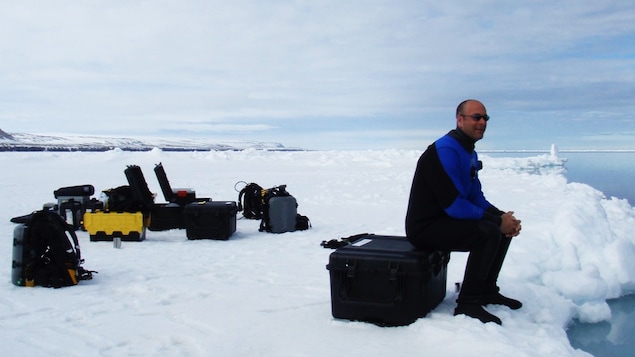 Mario Cyr assis sur une boîte d'équipement dans le Grand Nord.