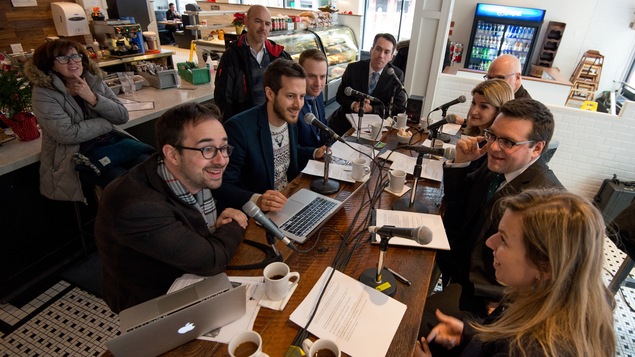 Raphaël Bouvier-Auclair, Philippe-Vincent Foisy, Louis Blouin, Nick Gamache, Yves Malo, Madeleine Blais-Morin, Daniel Thibault et Fannie Olivier assis dans un café pour enregistrer l'émission.