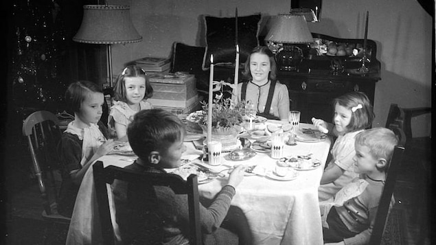 Un groupe d'enfants autour d'une table décorée de chandeliers, à l'occasion du temps des fêtes.