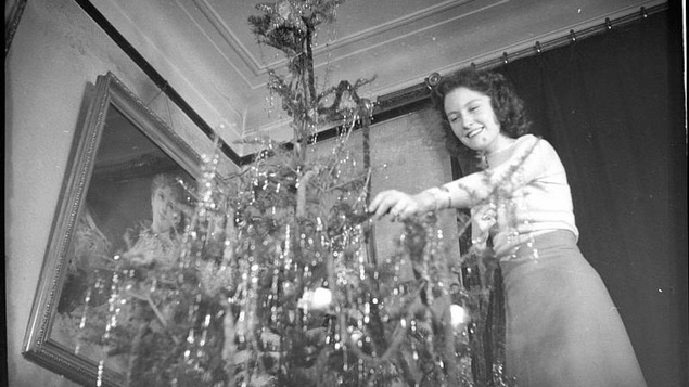 Une jeune femme décore un sapin de Noël en 1938.