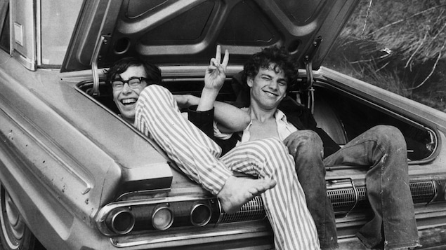 Deux jeunes hommes assis dans le coffre d'une voiture.