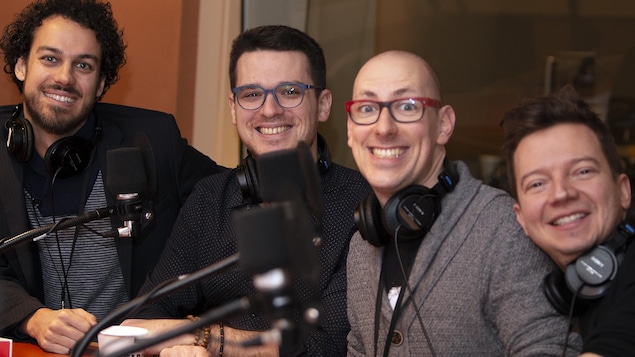 Quatre hommes sourient à la caméra.