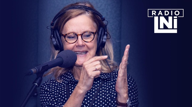 Photo de Sylvie Potvin qui parle avec les mains, devant un micro de radio.