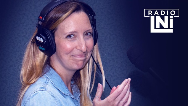 Photo de Sophie Thibeault qui applaudie en regardant la caméra, devant un micro de radio.