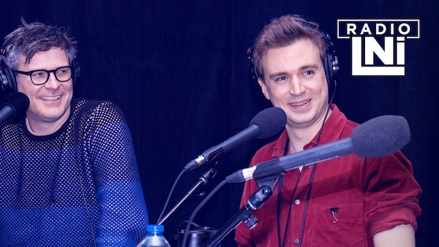 Photo de Stéphane Archambault et Arnaud Soly devant des micros de radio, un casque d'écoute sur les oreilles.