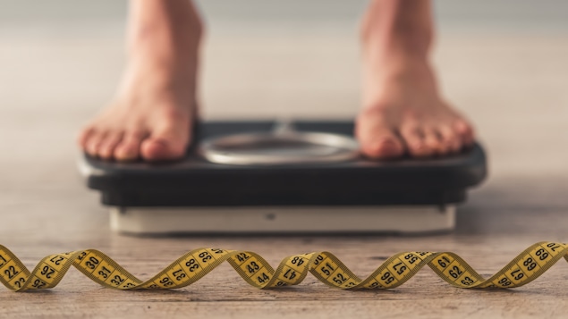 Une personne a les deux pieds sur une balance.