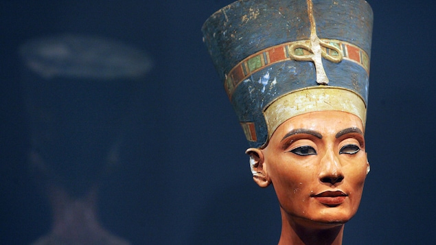 Une sculpture égyptienne représentant la tête de la reine avec un haut chapeau.