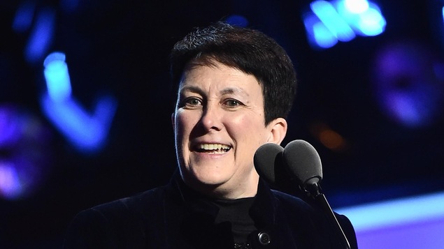 Au micro, tenant son prix entre les mains, Jennifer Higdon sourit, sa tête tournée vers la gauche. Elle est vêtue de noir et se détache d'un décor bleuté.