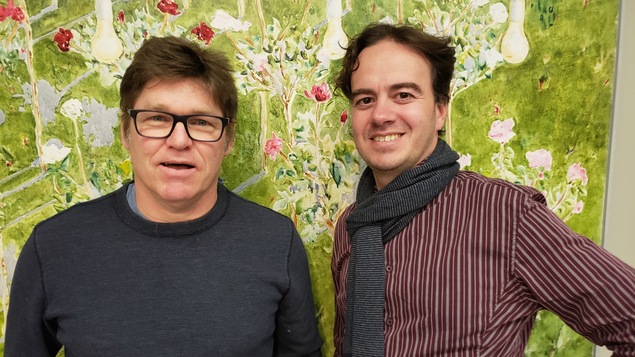 2 hommes devant une tapisserie à fleurs