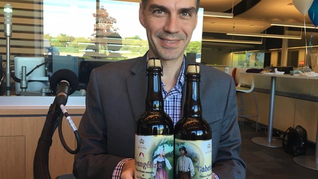 Sébastien Roy est assis en studio et tient deux bouteilles de bière.