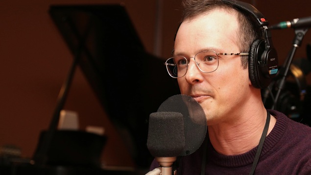 Simon Brousseau écoutant son interlocutrice dans un studio de radio.