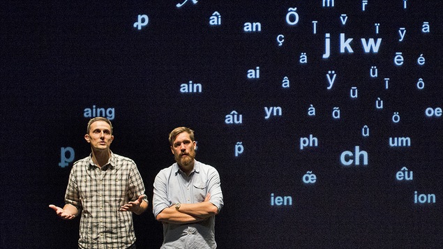 les deux comédiens et auteurs sont sur scène devant des lettres.