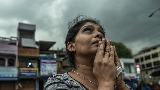 Une femme regardant vers le ciel, les mains jointes en prière.